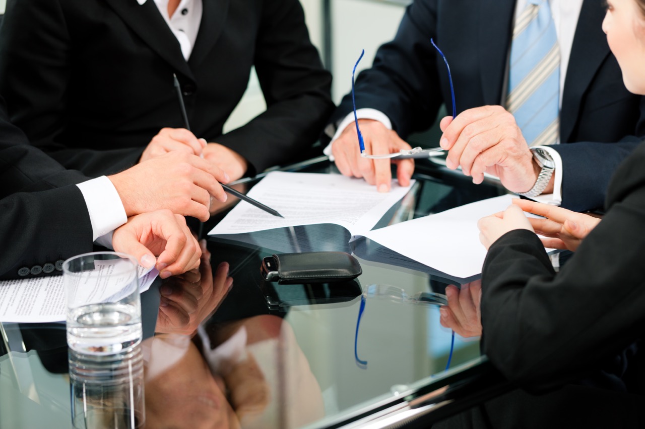 Business - meeting in an office; lawyers or attorneys discussing a document or contract agreement